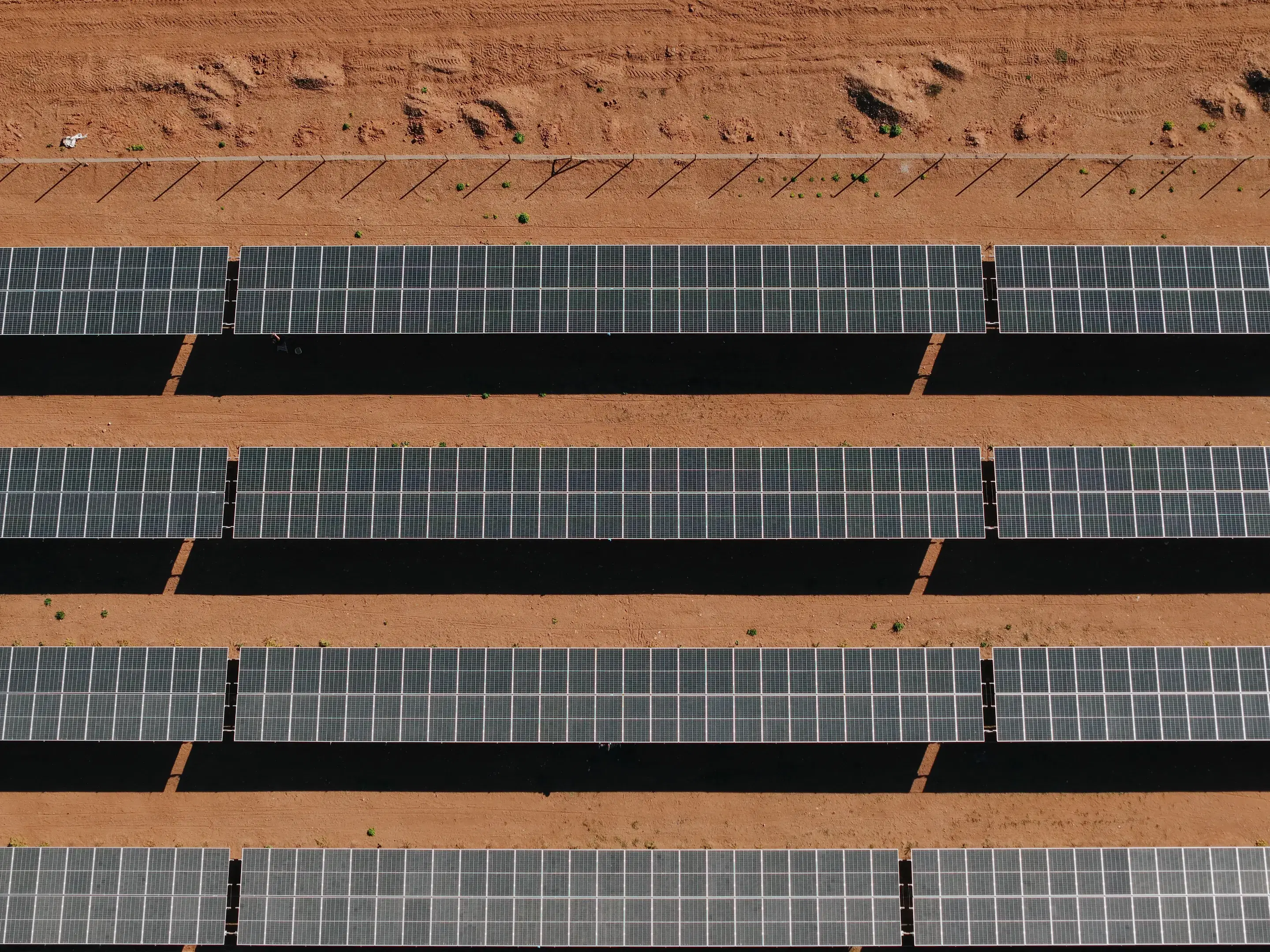 Filas de paneles solares sobre tierra roja en una planta de Rising Sun vistas desde el aire